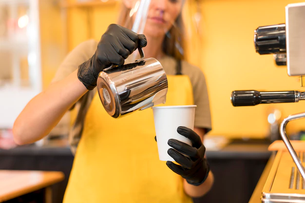 Barista pouring coffee in a white paper cup